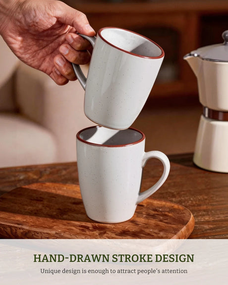 A hand holding a white ceramic mug with a contrasting dark green rim.