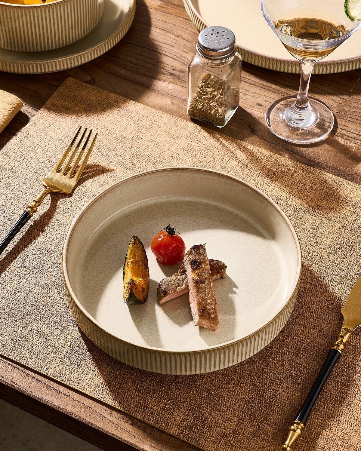 A cream-colored ribbed ceramic bowl holding a meal on a dining table.