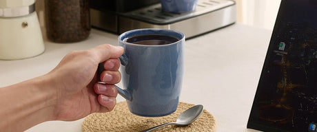 Blue ceramic mug beside a laptop on a coffee-bar workspace
