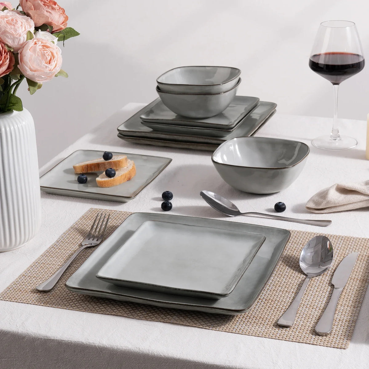 Gray square plates and bowls beside bread slices on a small plate