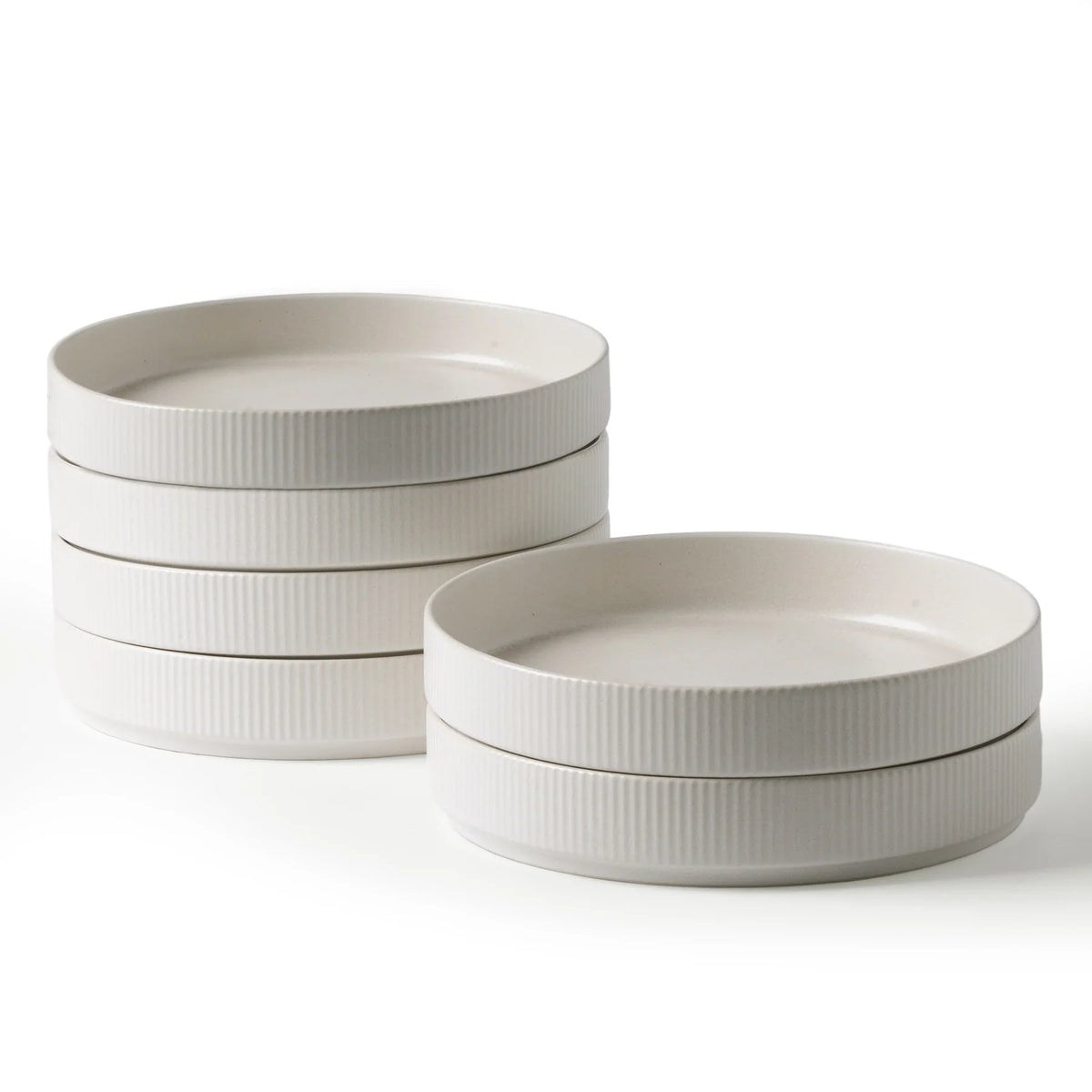 Wide white ceramic bowls with shallow sides stacked on a white background
