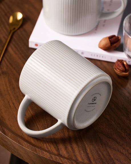 Close-up of a white ribbed ceramic mug showing its handle and marked underside