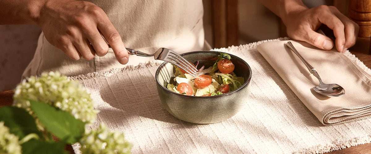 Individual ceramic bowl holding a green salad with tomatoes