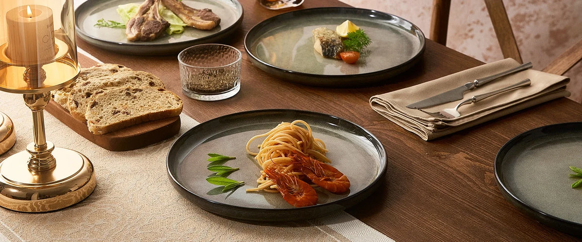 Dark-rimmed ceramic dinner plates photographed on a warm-lit table