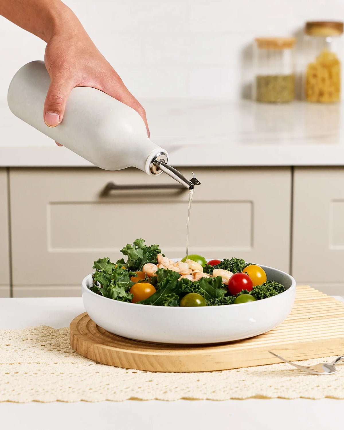 Ceramic oil dispenser pouring oil over a salad