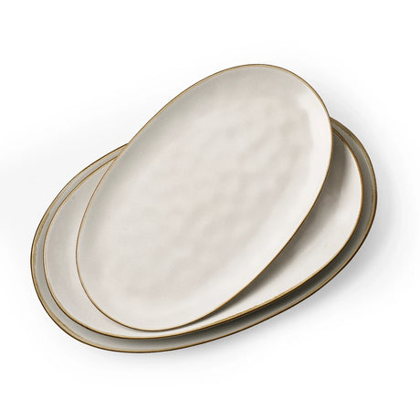 Three white oval ceramic serving platters with softly rippled rims