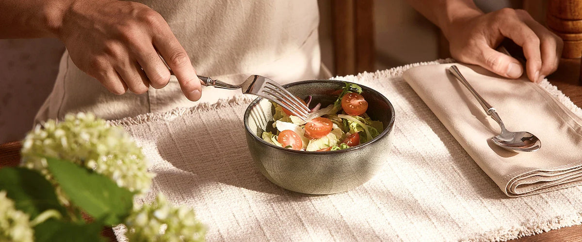 A diner eating green salad from an individual green ceramic bowl