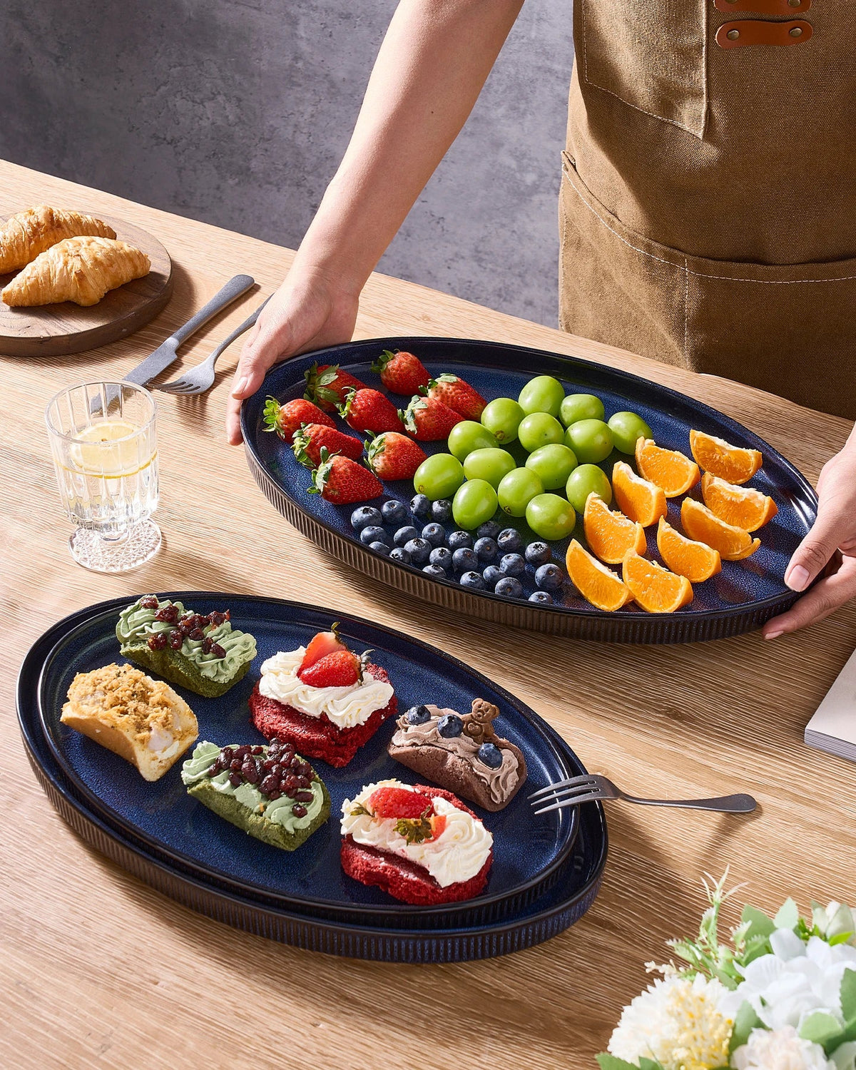 Blue oval ceramic platter holding fruit and being supported with two hands