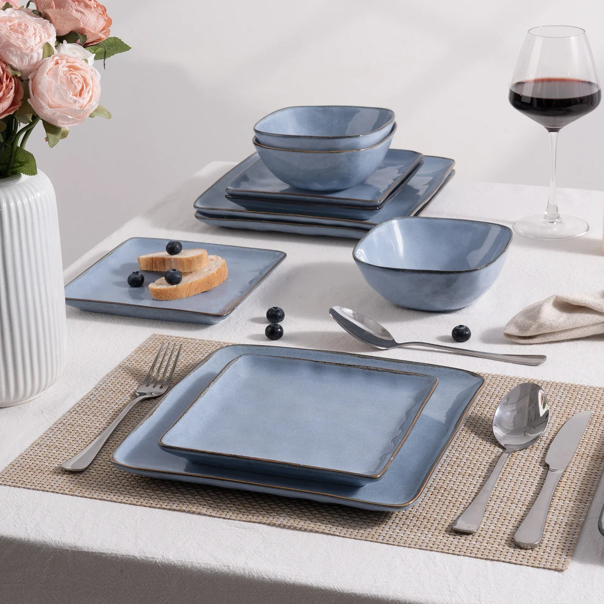 Blue square dinnerware on a woven placemat with flatware and a folded napkin nearby