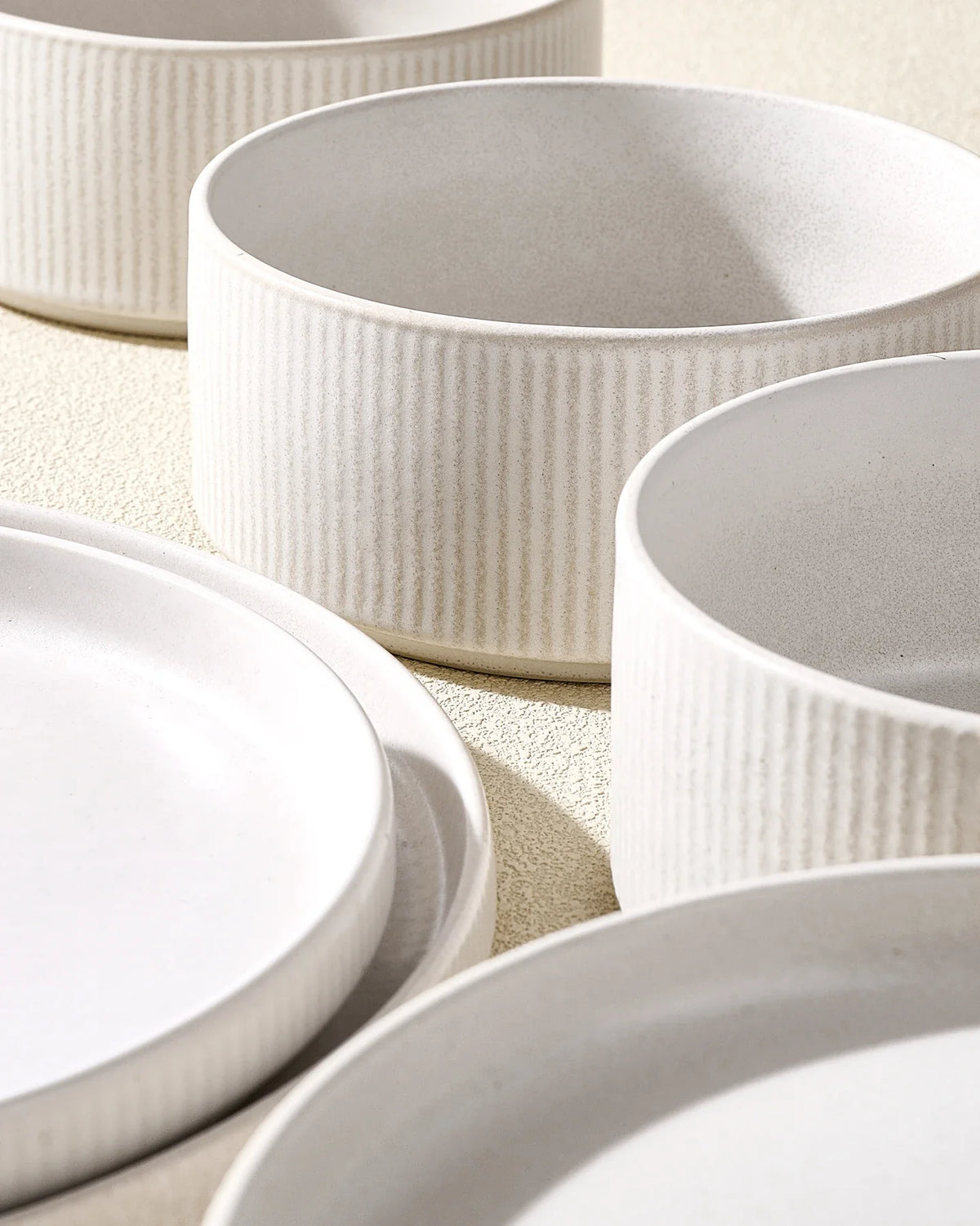 Close-up of matte white ribbed Famiware stoneware plates and bowls